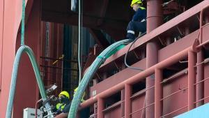 Varios trabajadores participan en la carga de bioetanol en el Port de Barcelona de un portacontenedores de Maersk.