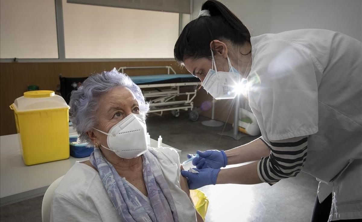 Una enfermera del CAP Poblenou de Barcelona administra a una mujer mayor de 80 años la vacuna de Pfizer, en el Casal de Gent Gran Quatre Cantons.