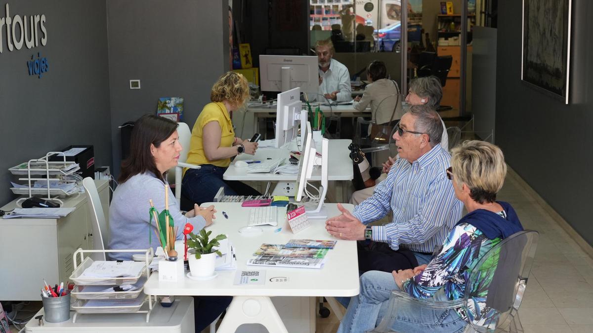 Varios empleados atienden a clientes en la agencia Resertours Viajes, localizada en Castelló.