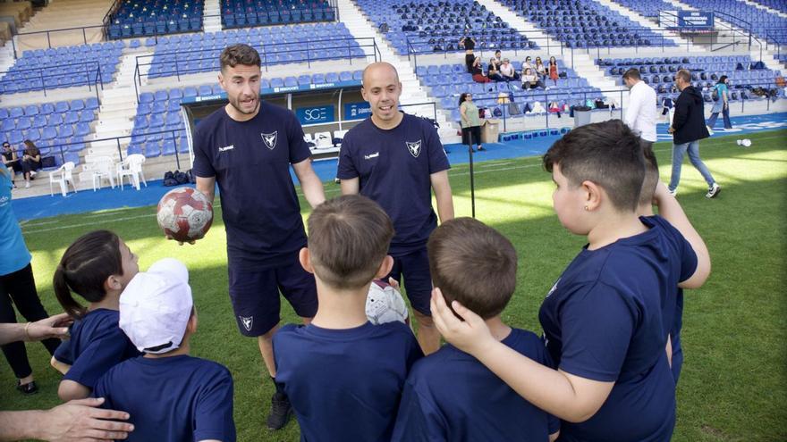 Jugadores del UCAM enseñando a los niños un juego a realizar con el balón. | JUAN CARLOS CAVAL