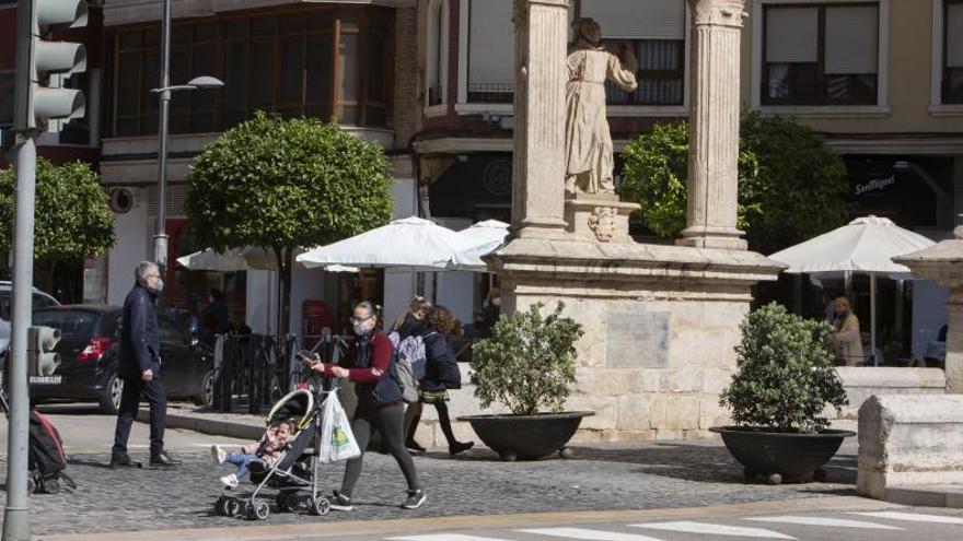 Una mujer pasea con un carro de bebé frente a los casalicios de Alzira. | PERALES IBORRA