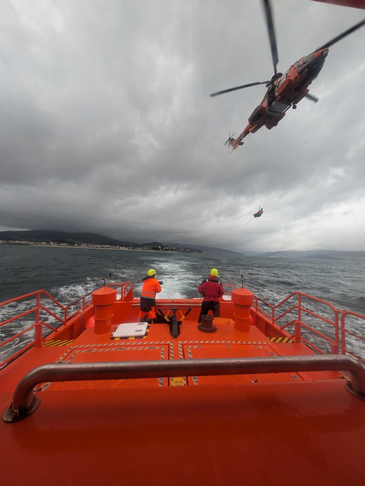 Un momento de las maniobras realizadas ayer por Salvamento Marítimo en Cangas, con un rescatador descendiendo por el cable desde el helicóptero Helimer 401.