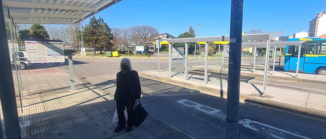 Una mujer obligada a esperar de pie el bus para Carril porque en su marquesina no hay donde sentarse, ayer.