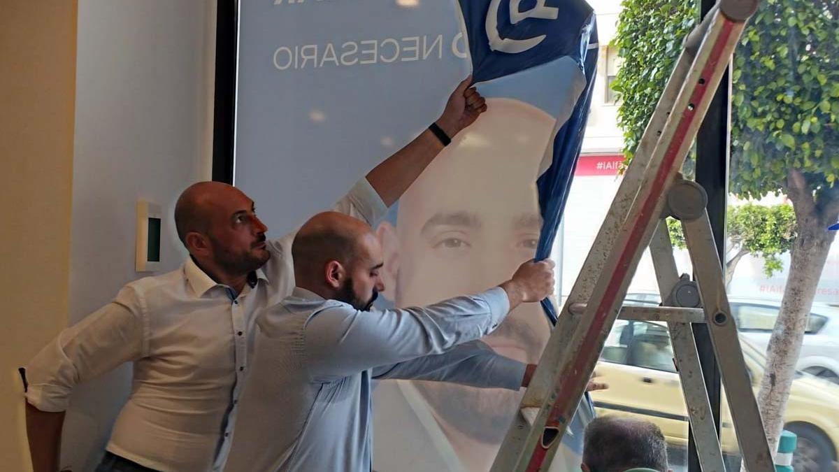 Carlos Pastor arrancando uno de los carteles en los que figuraba de candidato en la sede del PP