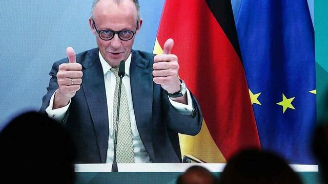El canceller alemany, Friedrich Merz, en pantalla, durant la inauguració d’una planta de xips a Dresden. | RONNY HARTMANN / AFP