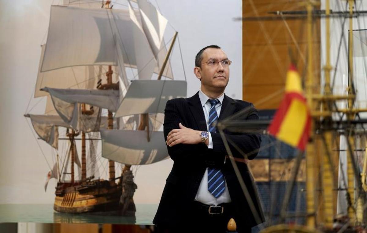 Rodrigo Pérez, profesor de la Escuela de Ingenieros Navales y comisario de la exposición, con una recreación del San Juan Nepomuceno a su espalda.