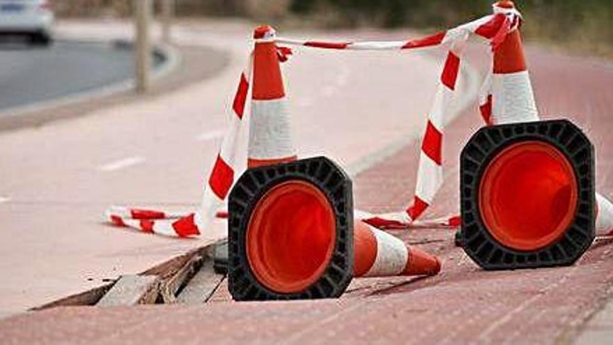 El tramo de la acera que se hunde y un ciclista pasa, ayer, junto a la zona defectuosa.