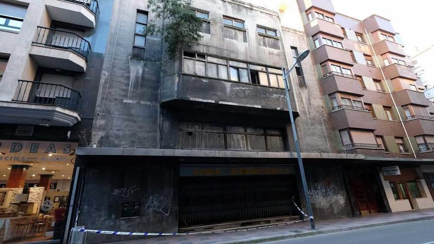 El edificio del antiguo cine Esperanza, con la acera cerrada y el árbol sobresaliendo en la fachada.