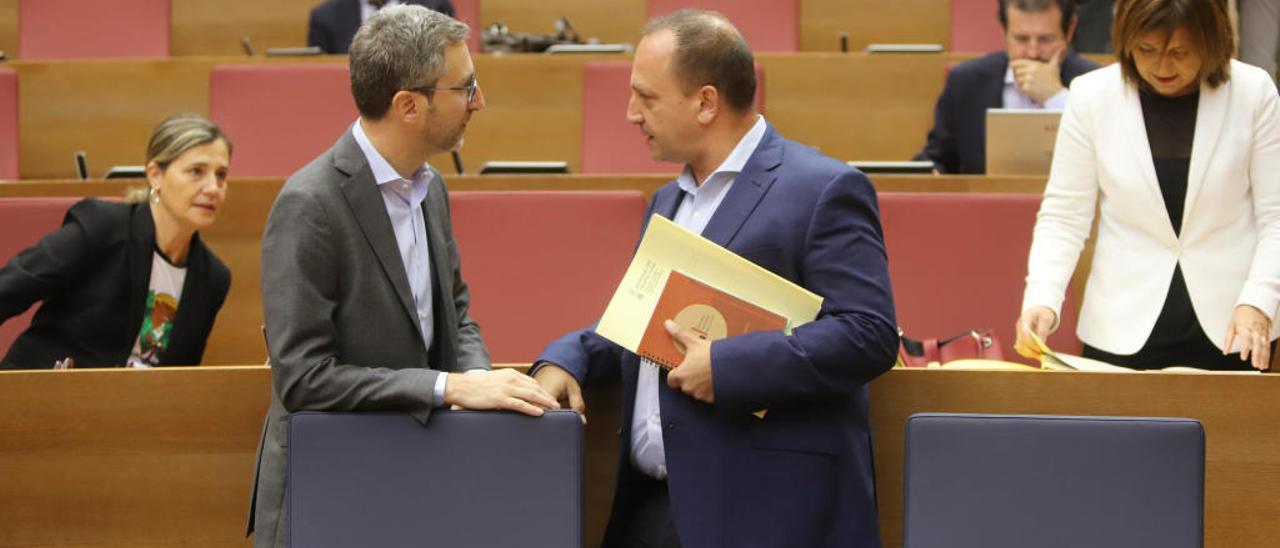 El conseller Arcadi España dialoga con el vicepresidente Martínez Dalmau en las Cortes.