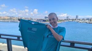 Sara Martínez muestra la camiseta de la Cursa Contra el Càncer que tendrá lugar el 31 de mayo en el Port de Barcelona.