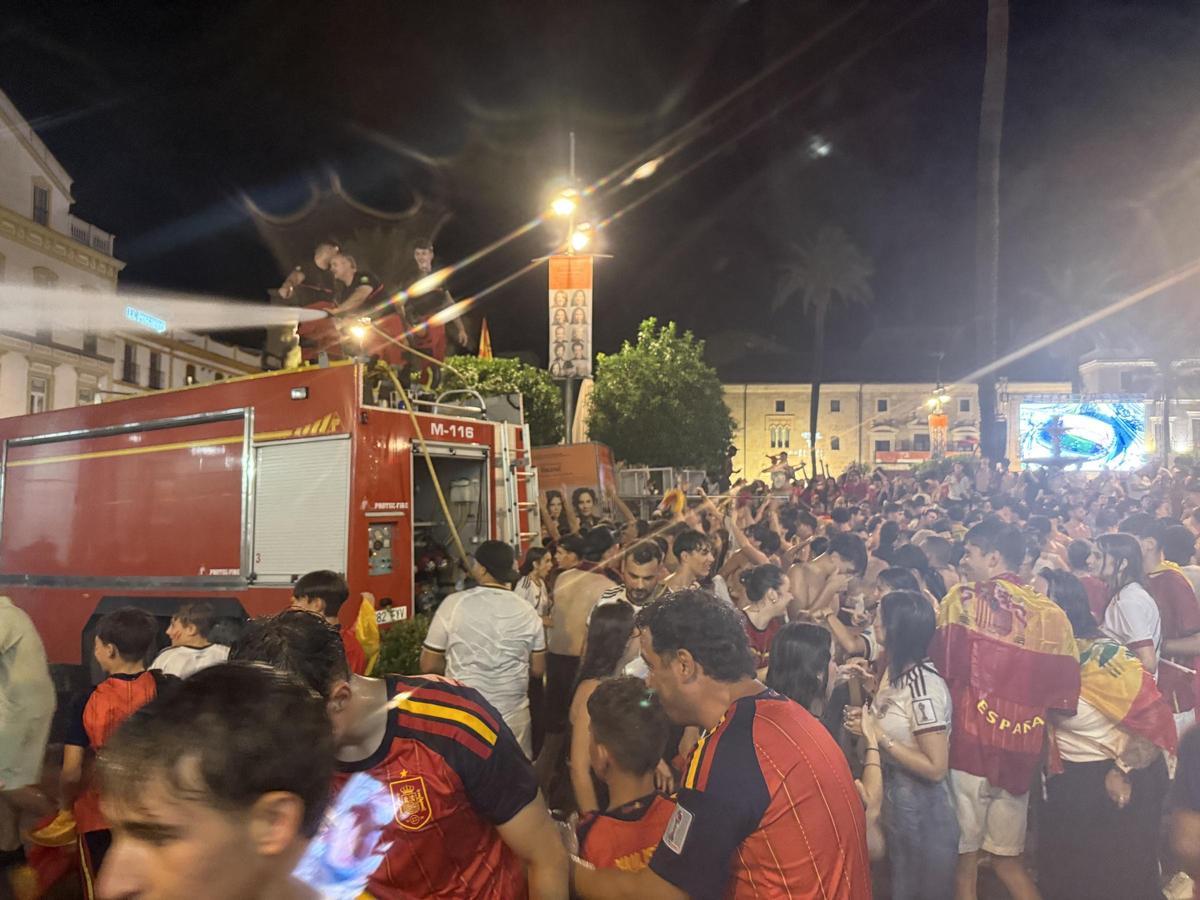 Los bomberos refrescan con sus mangueras a los aficionados durante la celebración en la Plaza de España de Mérida.
