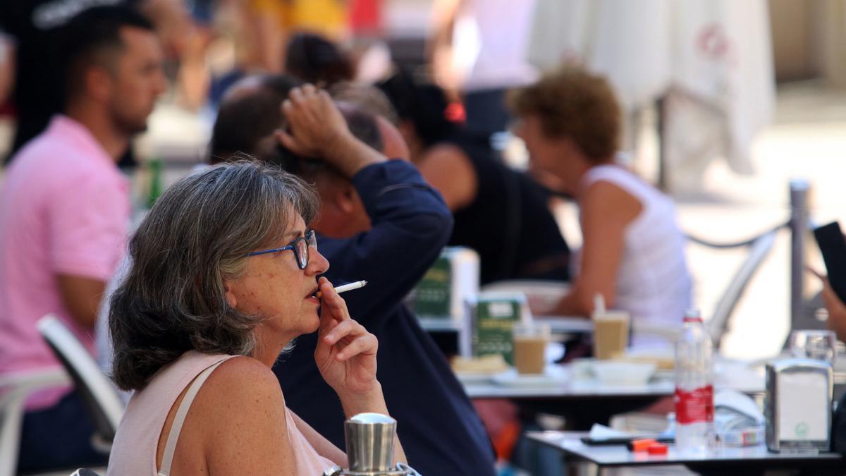 Personas fumando en terrazas y vías públicas durante el día en el que se ha decretado la prohibición de fumar en espacios públicos si no se respeta la distancia de seguridad establecida.