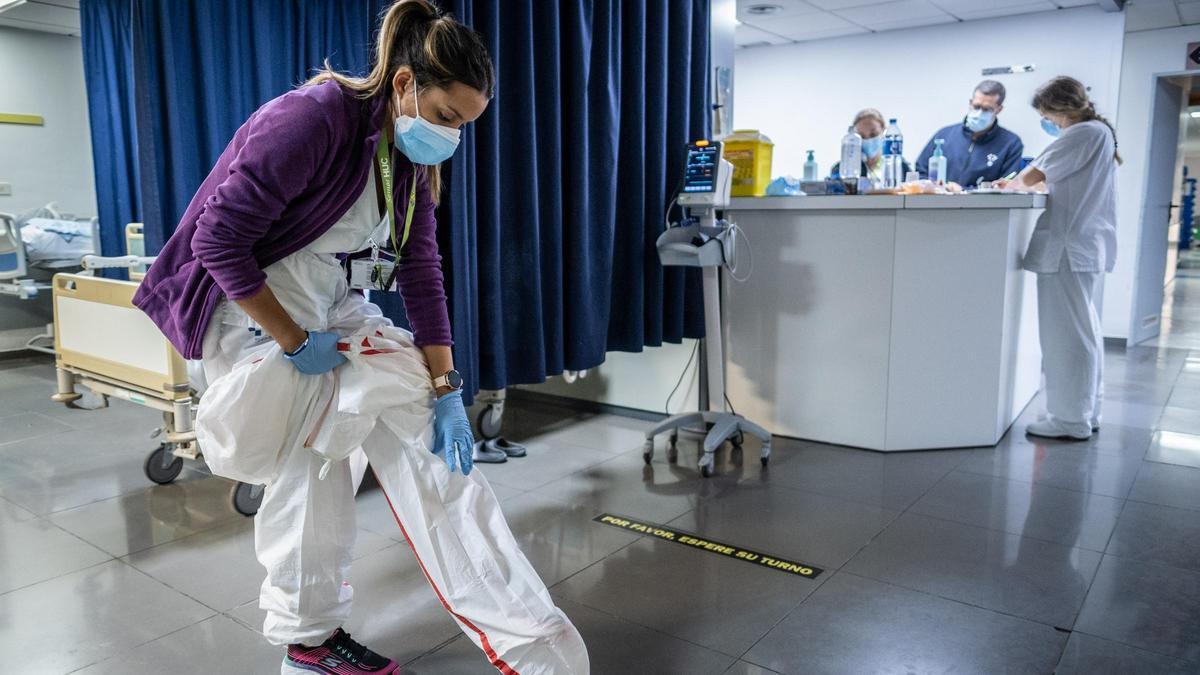 Una enfermera se prepara para atender a un paciente aislado por covid.