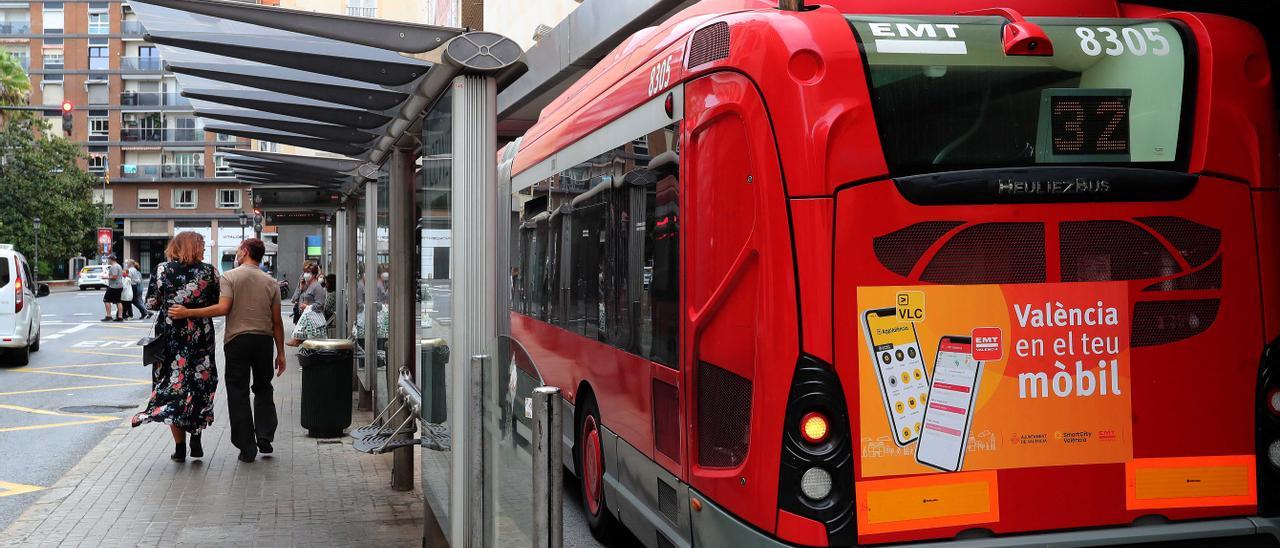 Una pareja pasea junto a uno de los autobuses de la EMT, en la parada de Pintor Sorolla.