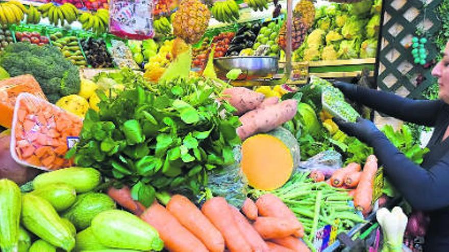 Una mujer, en un puesto de frutas y verduras.