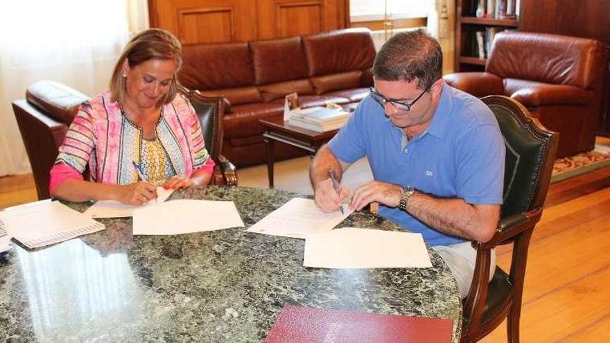 Carmela Silva y Miguel Domínguez, firmando el convenio. // FdV