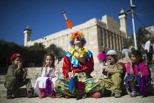 Un ciudadano judío disfrazado de payaso hace malabares junto a unos niños