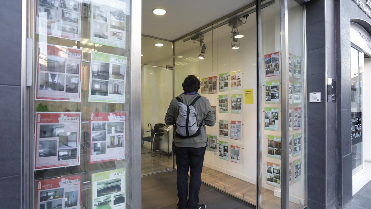 Un joven consulta la oferta de vivienda en el escaparte de una inmobiliaria de Zaragoza.