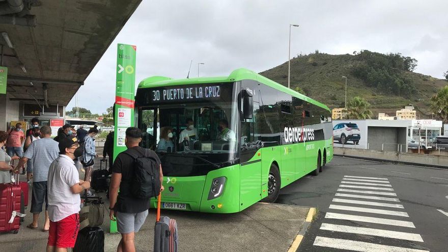 Una guagua y pasajeros en una estación de Tenerife.