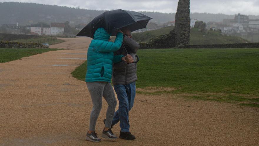 Dos personas se resguardan de la lluvia en O Grove.