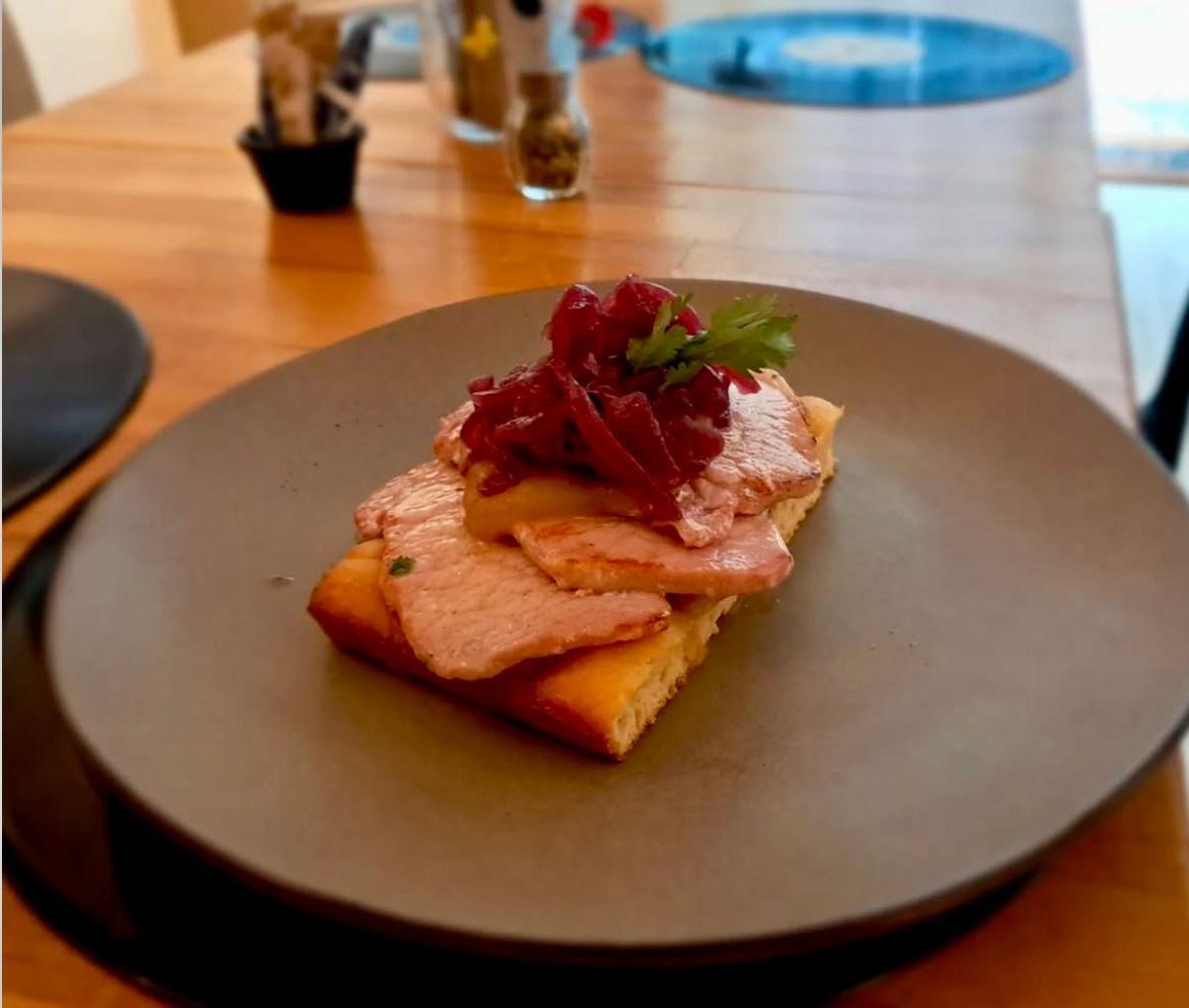 Tostada casera de focaccia con lomo de cerdo, salsa de manzana y salvia y cebolla caramellata