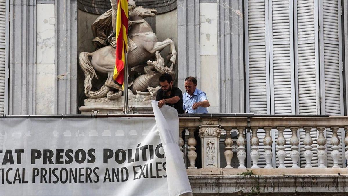 Dos trabajadores de la Generalitat retiran la pancarta.