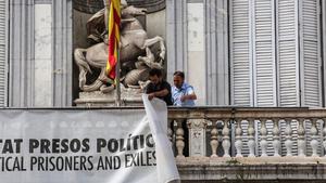 Dos trabajadores de la Generalitat retiran la pancarta que colgaba del Palau, el pasado 27 de septiembre.