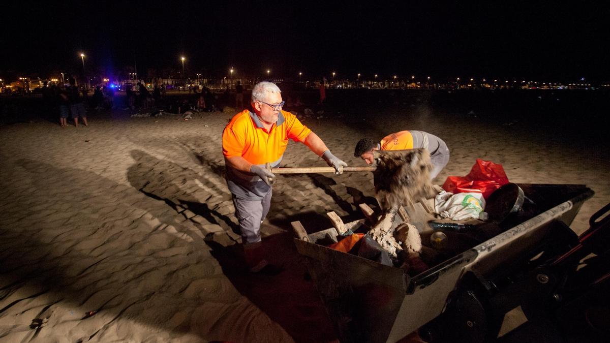 Un operario recoge los residuos de la playa y los tira a un contenedor.