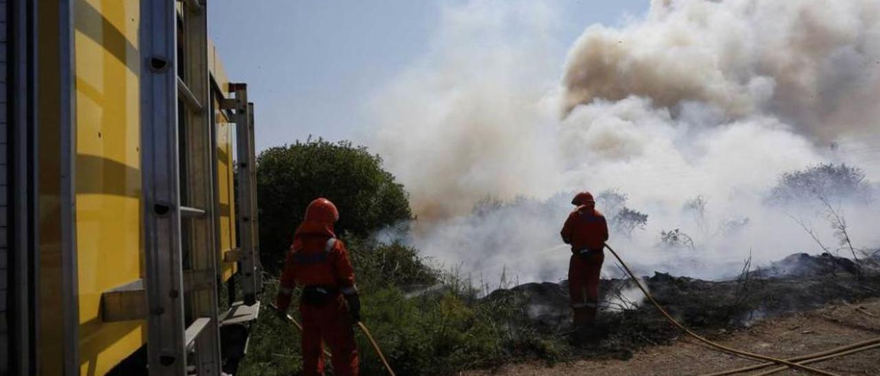 Los bomberos, trabajando en las labores de extinción del incendio en la zona de Barredo.