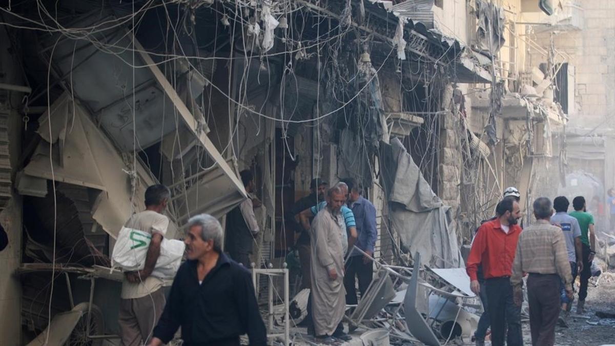 Miembros de la defensa civil siria y otras personas inspeccionan los edificios destrozados tras un bombardeo en el barrio de Al-Qaterji, controlado por los rebeldes, en Alepo, el 11 de octubre.