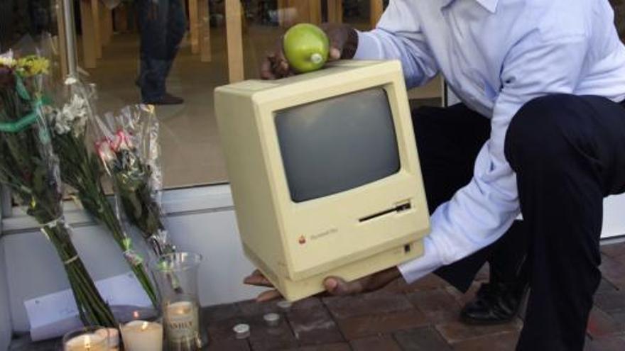 Un hombre deja un antiguo Macintosh ante un ramo de flores en recuerdo a Jobs.