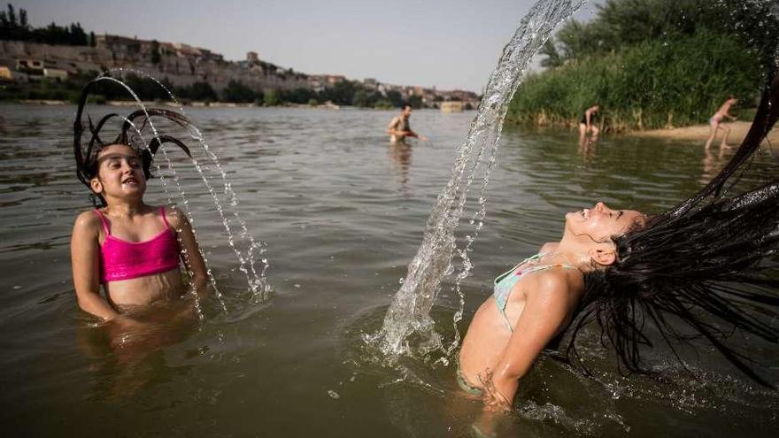 Varias personas juegan y se bañan en el Duero para sobrellevar el calor.