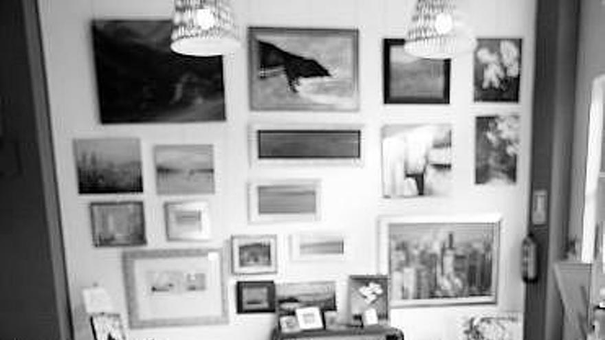 Milena Londoño, en su establecimiento, con los cuadros al fondo.