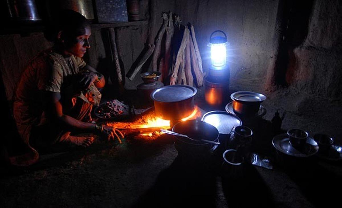 Una mujer cocina este domingo a la luz de una linterna solar distribuida por la ONG AAS, en el Parque Nacional de Sanjay Gandhi, cerca de Bombay (India). En este suburbio en el que no hay electricidad, el proyecto llegará a una treintena de familias.