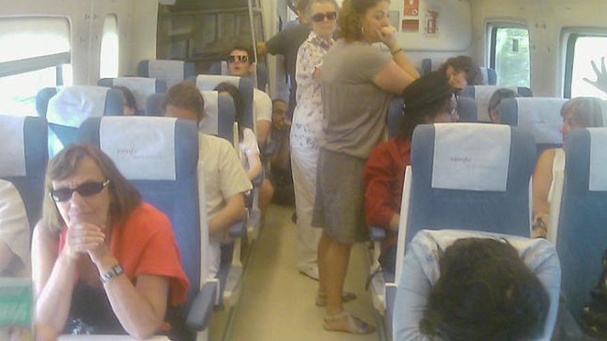 Diversos passatgers es recolzen en els seients en un passadís d&#039;un tren que anava ahir cap a Barcelona.