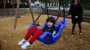 Bruno sonríe mientras su madre le columpia en el parque de la Vila Olímpica.