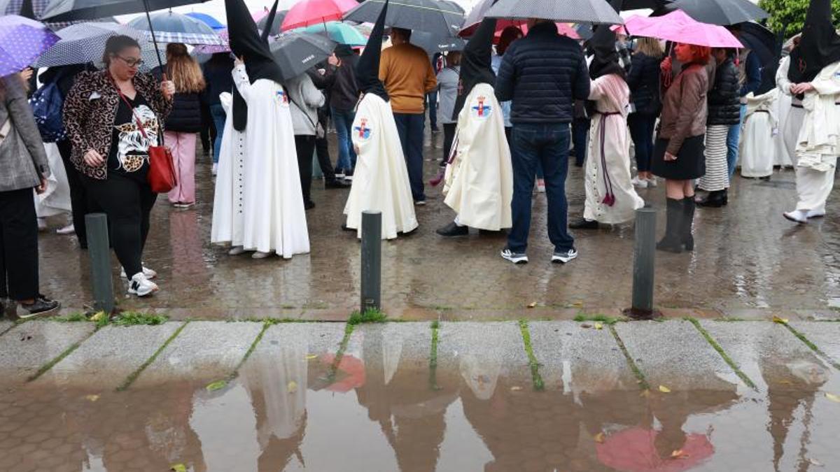 Nazarenos de la Hermandad del Cautivo de San Pablo salen de la Iglesia tras suspenderse por la lluvia su estación de penitencia.