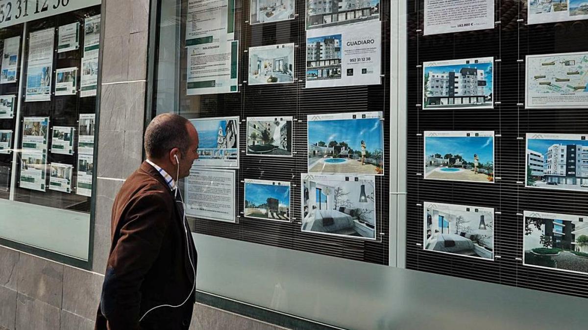Un hombre mira los anuncios en el escaparate de una agencia inmobiliaria.
