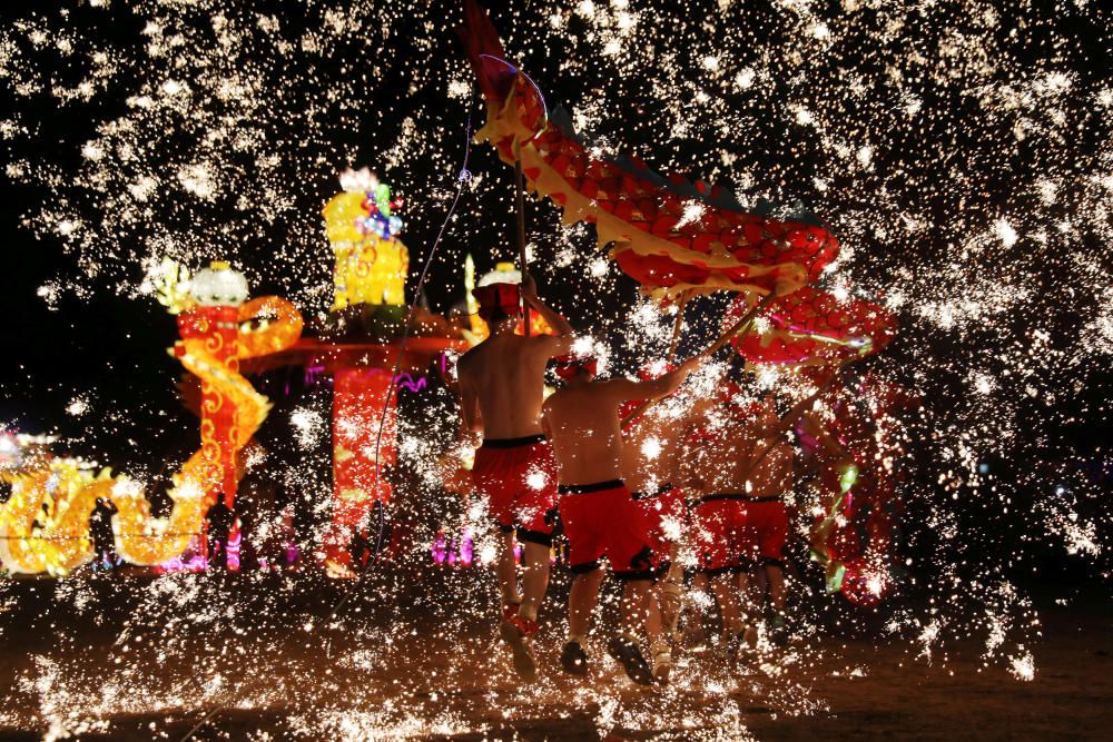 Folk artists perform a fire dragon dance under a ...