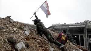 Un soldado del Ejército sirio coloca una bandera nacional durante una batalla con combatientes rebeldes en Alepo. 