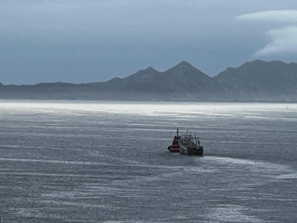 El pesquero, remolcado saliendo de la ría