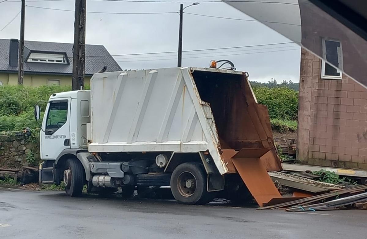 Camión do servizo de recollida de lixo aparcado diante dun taller