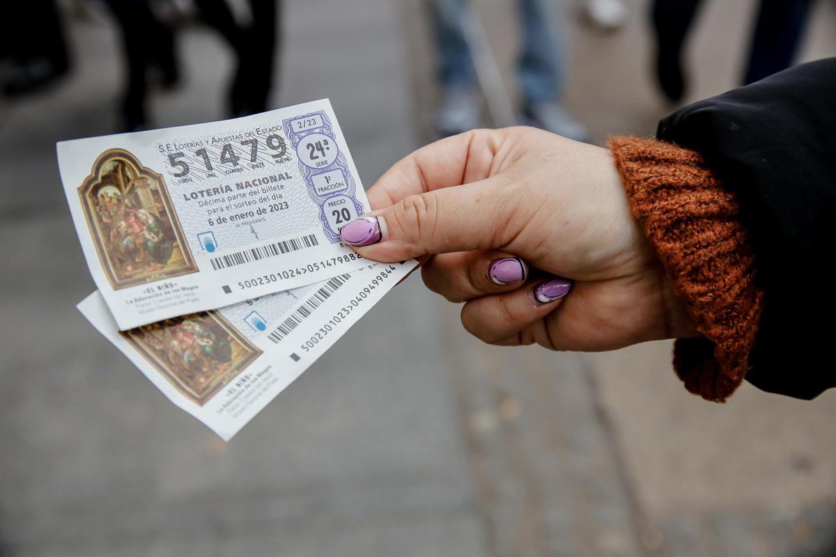 Una mujer sostiene dos décimos para el Sorteo Extraordinario del Niño.