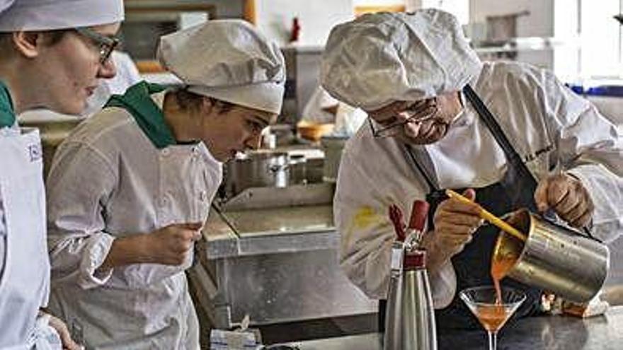 Dos alumnas observan una de las técnicas culinarias que les enseña el profesor Juan Luis Benito.