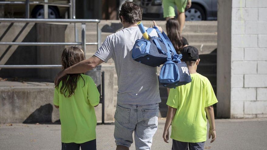 Un padre carga con las bolsas de deporte de sus hijos, en un club deportivo de Barcelona.