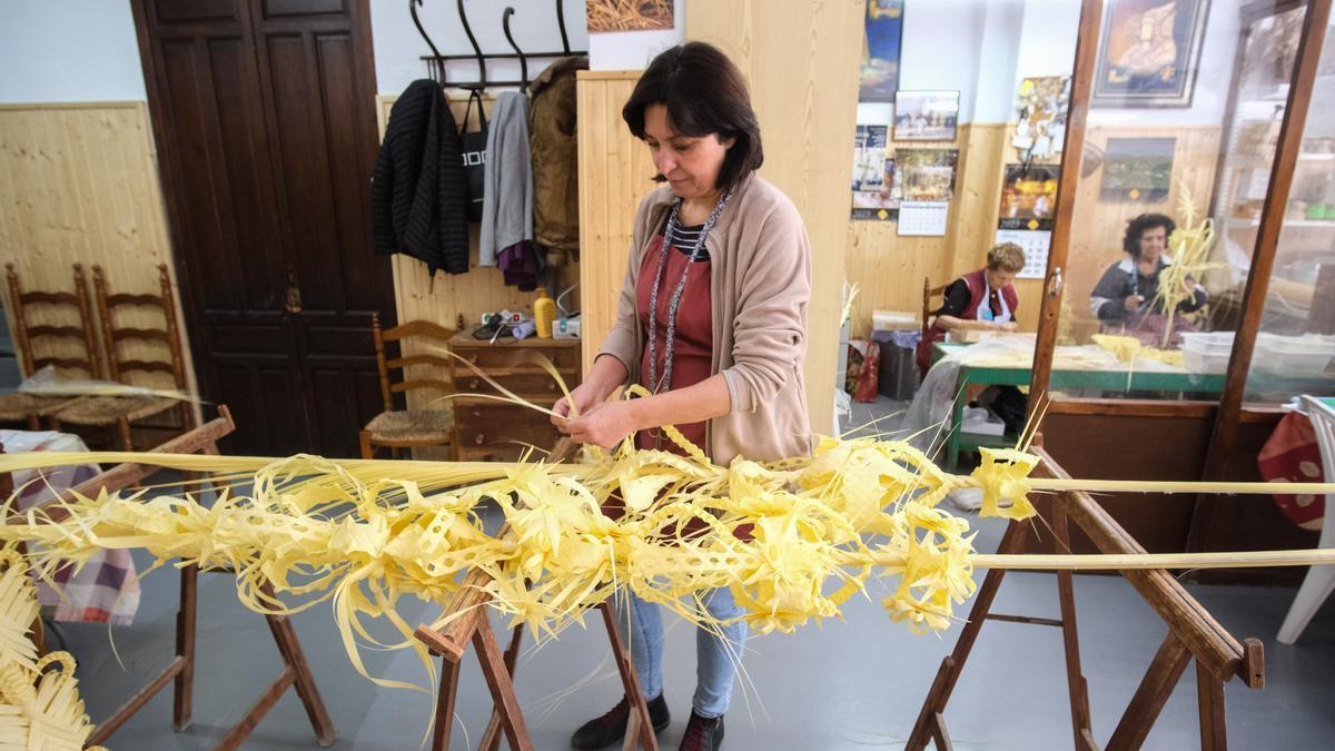 Paqui Serrano trenza una palma blanca grande en el taller familiar de Serrano Valero en Elche.
