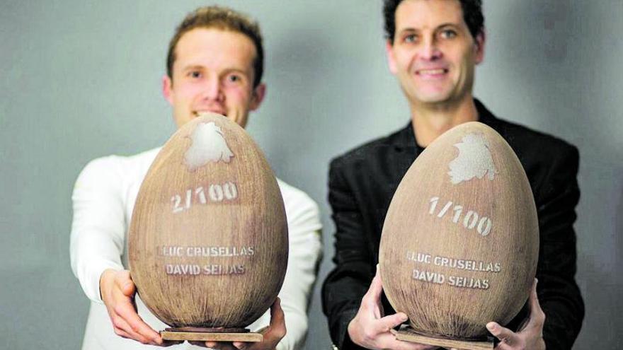 Lluc Crusellas (a l’esquerra) i David Seijas mostren els dos primers exemplars de la mona que han creat plegats; al seu interior hi ha una ampolla de vi de l’Empordà. | DDG