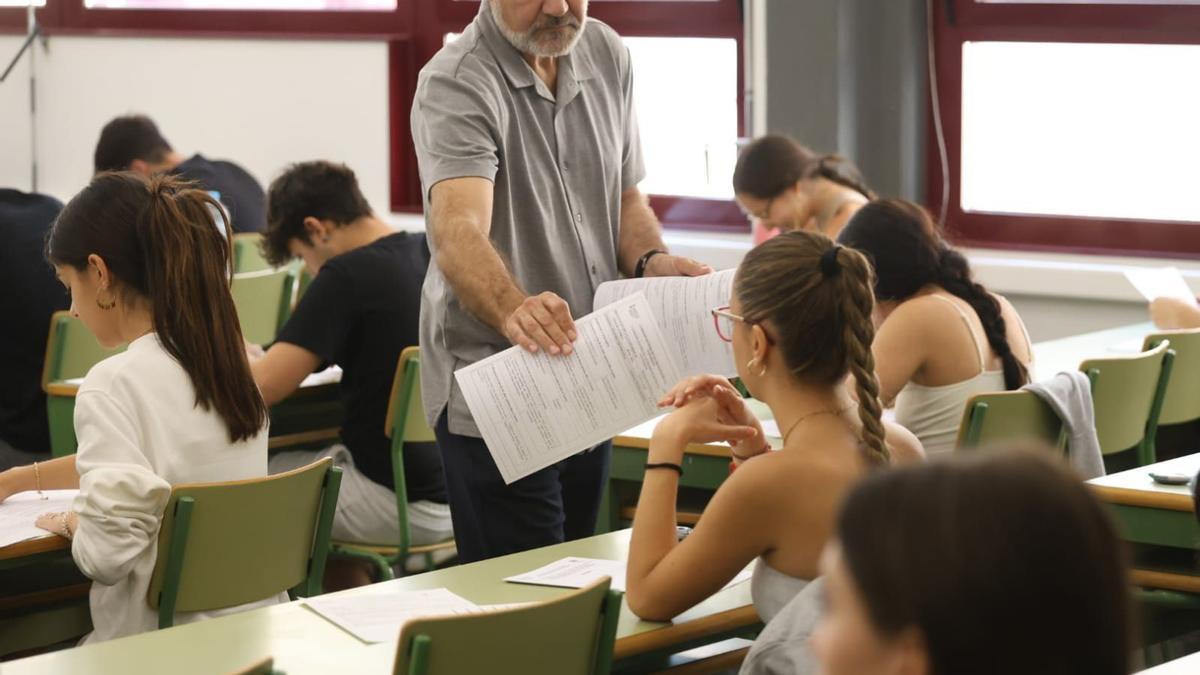 Imagen de archivo de un profesor repartiendo exámenes en la EBAU 2023.