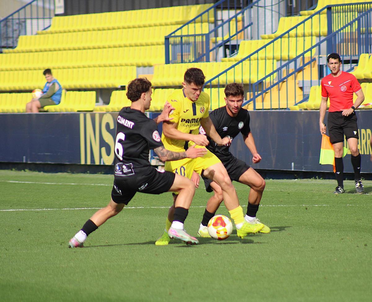 Albert García, delantero del Villarreal B, rodeado de defensas del equipo malagueño.
