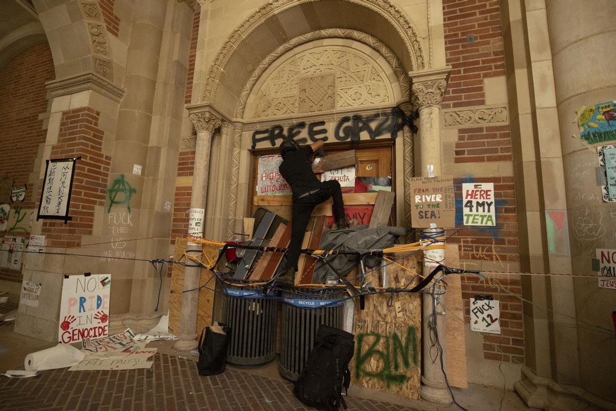 A pro-Palestinian demonstrator blocks the entrance to a building on the UCLA campus Wednesday, May 1, 2024, in Los Angeles. (AP Photo/Ethan Swope)